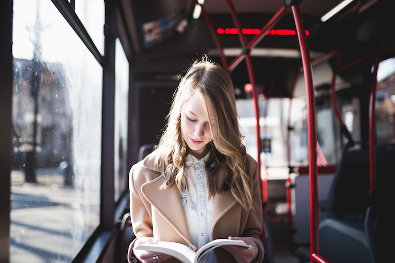 Beautiful-young-woman-sitting-in-city-bus-and-reading-a-book